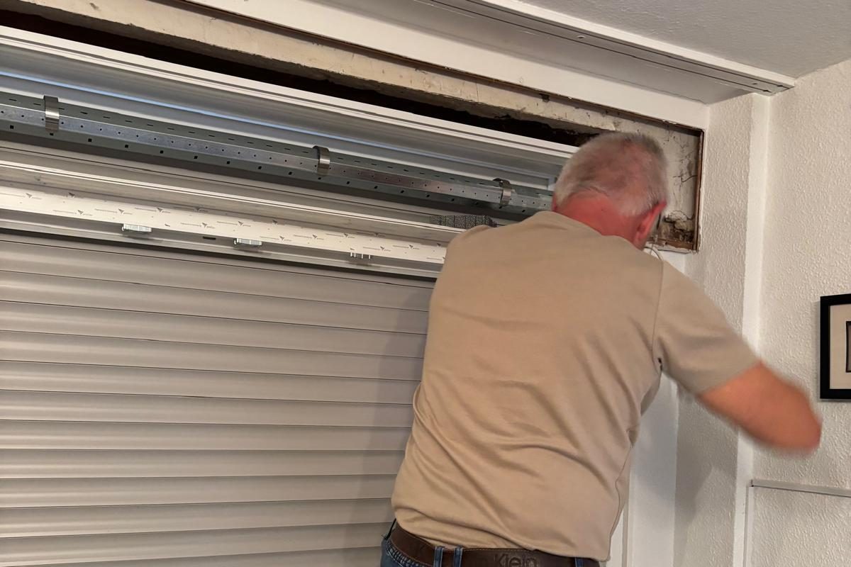 Monteur arbeitet am Rollladenkasten über einem Fenster